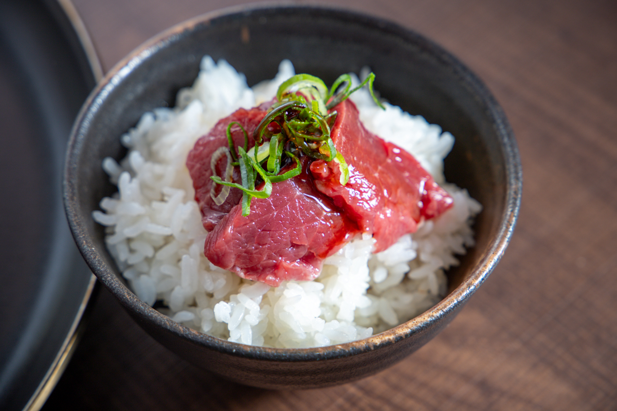 白いご飯に馬刺しと小ねぎをのせた一皿